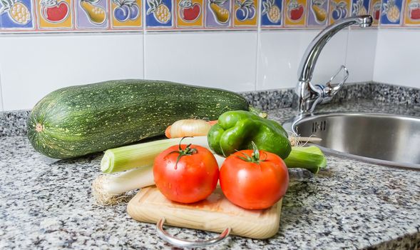 Fresh vegetables on cutting board in the kitchen over granite worktop