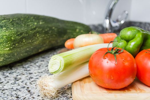 Fresh vegetables on cutting board in the kitchen over granite worktop