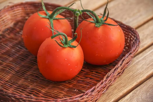 Fresh tomatoes in a basket on a wooden table