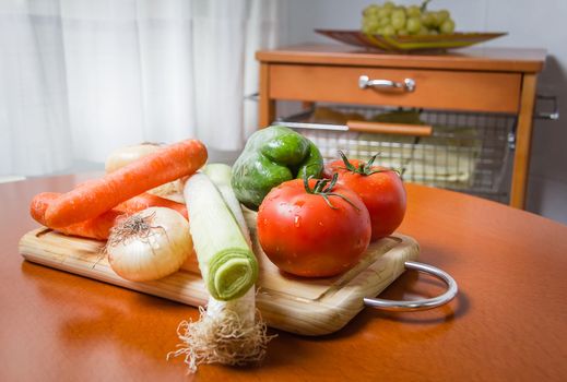 Fresh vegetables on cutting board in a wooden kitchen table