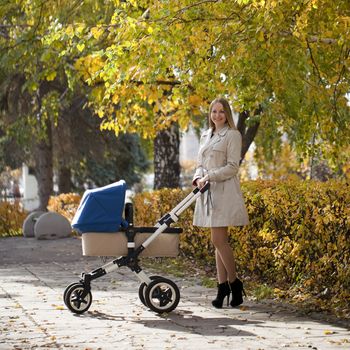 Mother with baby stroller for a newborn in autumn park