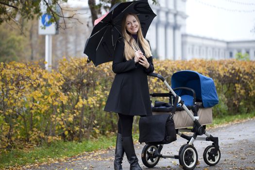Mother with baby stroller for a newborn in autumn park