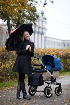 Mother with baby stroller for a newborn in autumn park