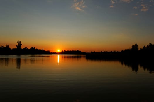 Colorful sunset over tranquil water surface.