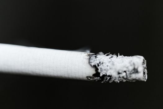 Smoking a cigarette against a dark background