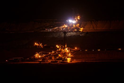 Coal mining in an open pit with huge industrial machine at night shoot