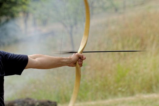 archery man shooting arrow with bow in the nature