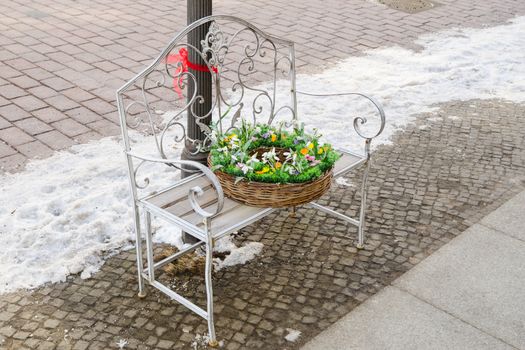 Wicker basket with spring flowers on the wrought iron bench