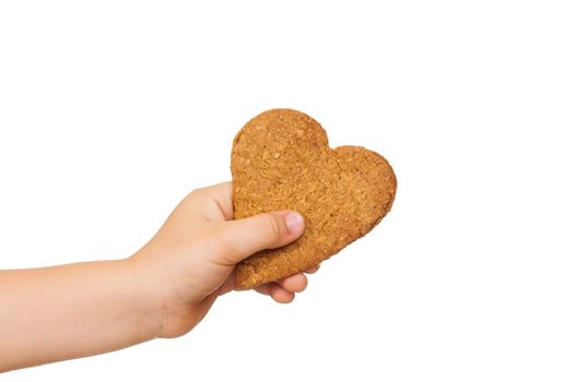 A child's hand is holding a love shaped gingerbread cookie. Isolated on white.