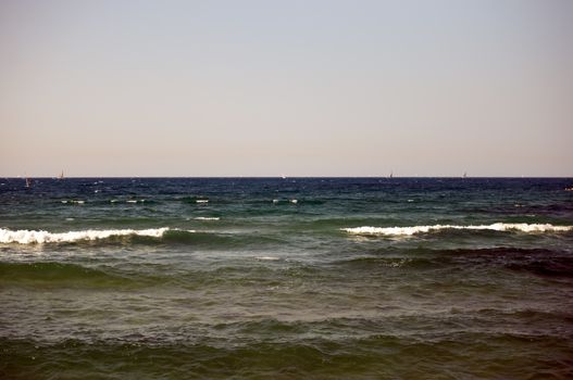 Water sports: windsurfer with bright colored sail . Tel Aviv marina. Israel.