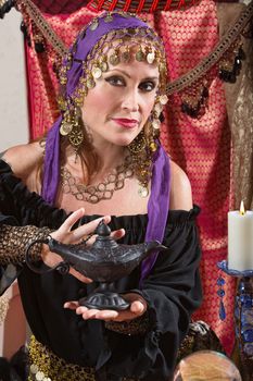 Pretty female gypsy fortune teller rubs a magic lamp