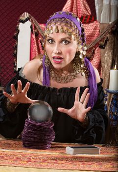 Charming Caucasian woman in headscarf waving hands over crystal ball