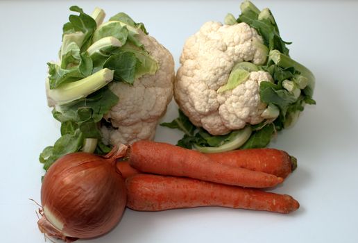 Freshly cut cauliflower cabbage , carrots and onion isolated on white .