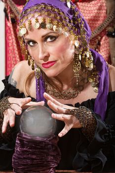 Pretty lady waving hands over crystal ball