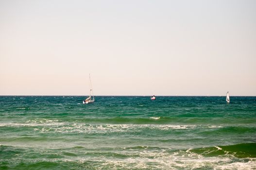 Water sports: windsurfer with bright colored sail . Tel Aviv marina. Israel.