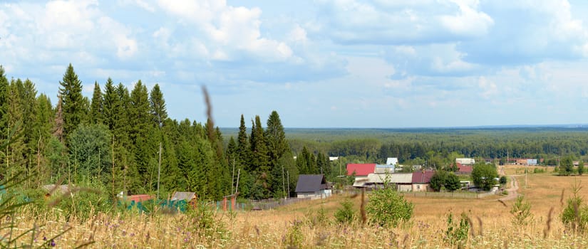 View from the hill to the village houses in the mixed forest