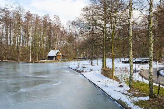 Springtime european park with frozen water in channel