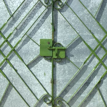 Green metal gate in fron of silver door
