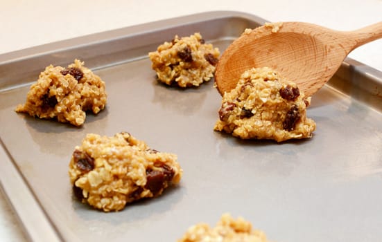 Oatmeal raisin cookie dough spooned onto baking sheet with selective focus
