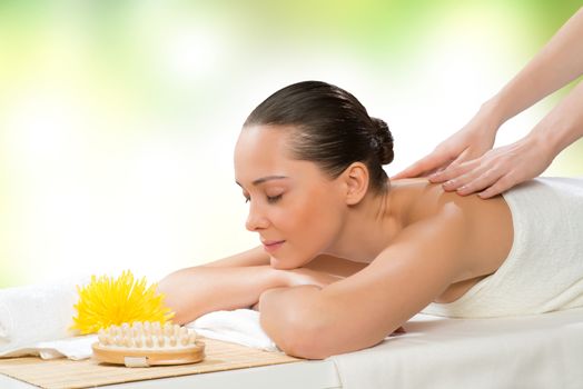 beautiful spa woman lying on the couch, in front of her flower and rolled towel