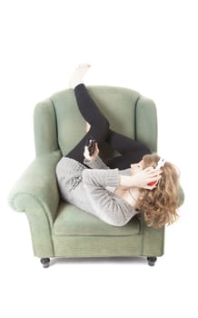 young pretty woman listening to music in armchair against white background