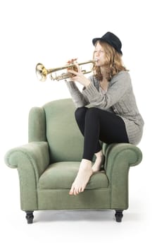 young pretty woman playing the trumpet on armchair against white background