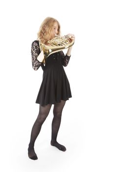 young woman in black playing  french horn against white background