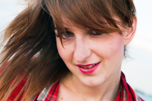 Portrait of a pretty fashionable, young woman in a chequered red shirt on the beach