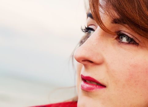 Pretty young woman looking at the ocean in a romantic way. Face portrait