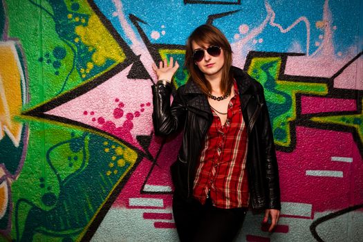 Stylish fashionable girl posing against colorful graffiti wall. Fashion, trends, subculture