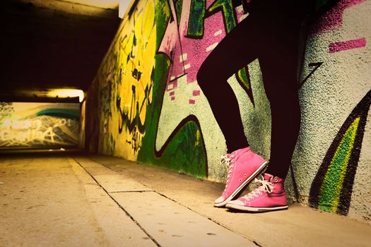Close up of pink sneakers worn by a teenager. Grunge graffiti wall, retro vintage style