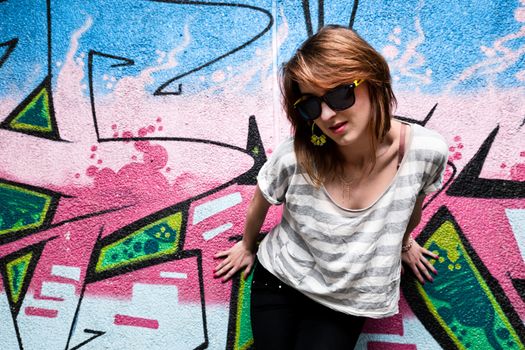 Stylish fashionable girl portrait against colorful graffiti wall. Fashion, trends, subculture.