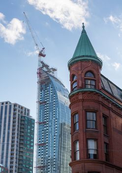 Construction of new high rise buildings in Toronto above traditional red brick Flatiron building rapidly changing the skyline of the Ontario city