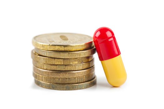 Closeup view of stack of coins and pill over white background