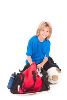 a young boy, ready for going to play football, with his sportbag and football