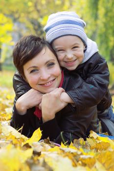 Happy mother and son lying on autumn leaves