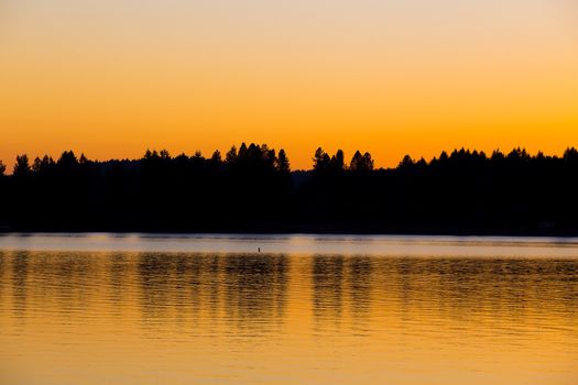 This beautiful sunset over water is photographed in an abstract way to show the color and lines of the land across the lake.