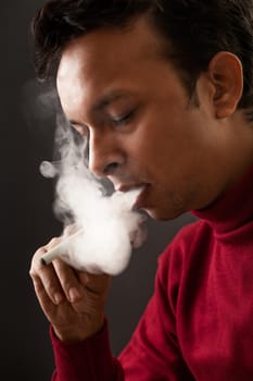 Smoking by indian man using electronic cigarette over gray background