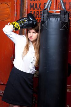 Girl in a business suit near punch bag