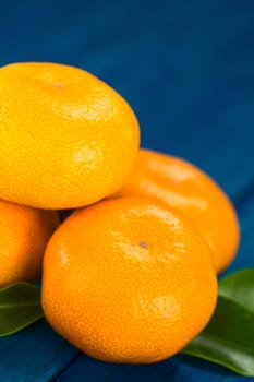 Mandarins with leaves on blue wood (Selective Focus, Focus on the two mandarins in the front) 