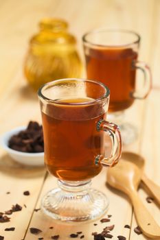 Fresh hot chocolate herbal tea made of cacao shell flakes, which is rich in flavonoids and antioxidants, served in glasses (Selective Focus, Focus on the front of the rim of the first glass)