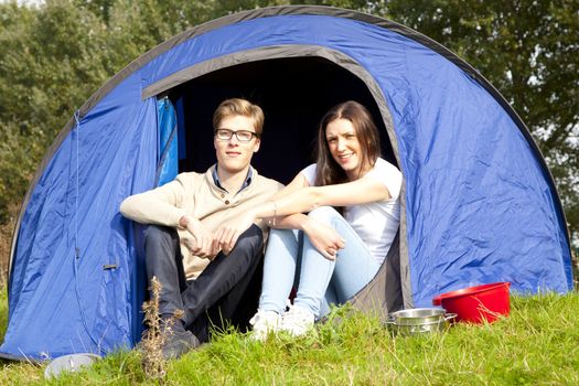 Young man and woman camping with blue tent