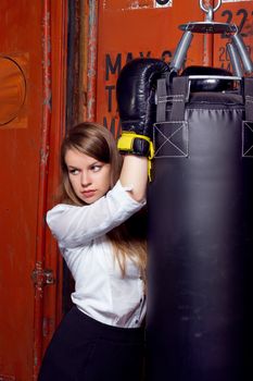 Girl in a business suit near punch bag