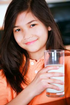 Biracial young girl holding glass of milk 