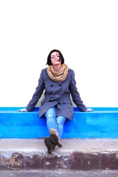 Beautiful young girl sitting against yellow wall