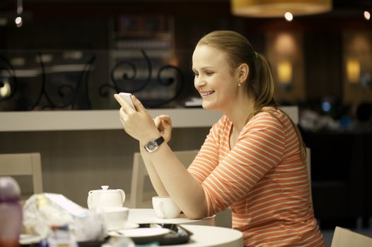 Young beautiful woman chatting on smartphone sitting in cafe