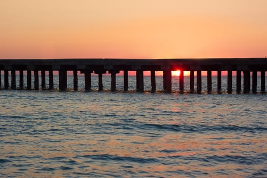 Old sea pier during the beautiful sunset over the sea coast
