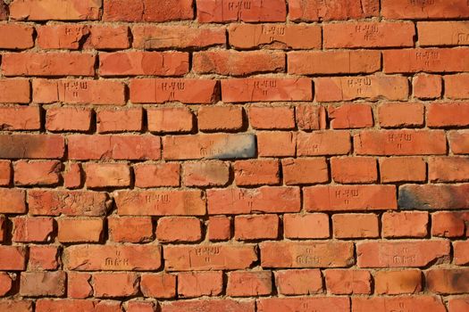 Red brick wall with clay mortar in bright sunlight