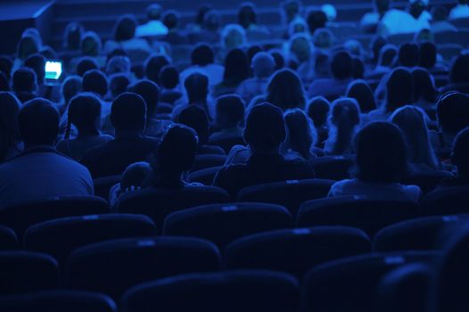 Audience in the cinema. Silhouette shot from back in blue light.