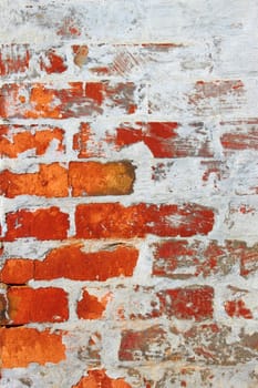 Old wall from a red brick partially covered by cement mixed with lime